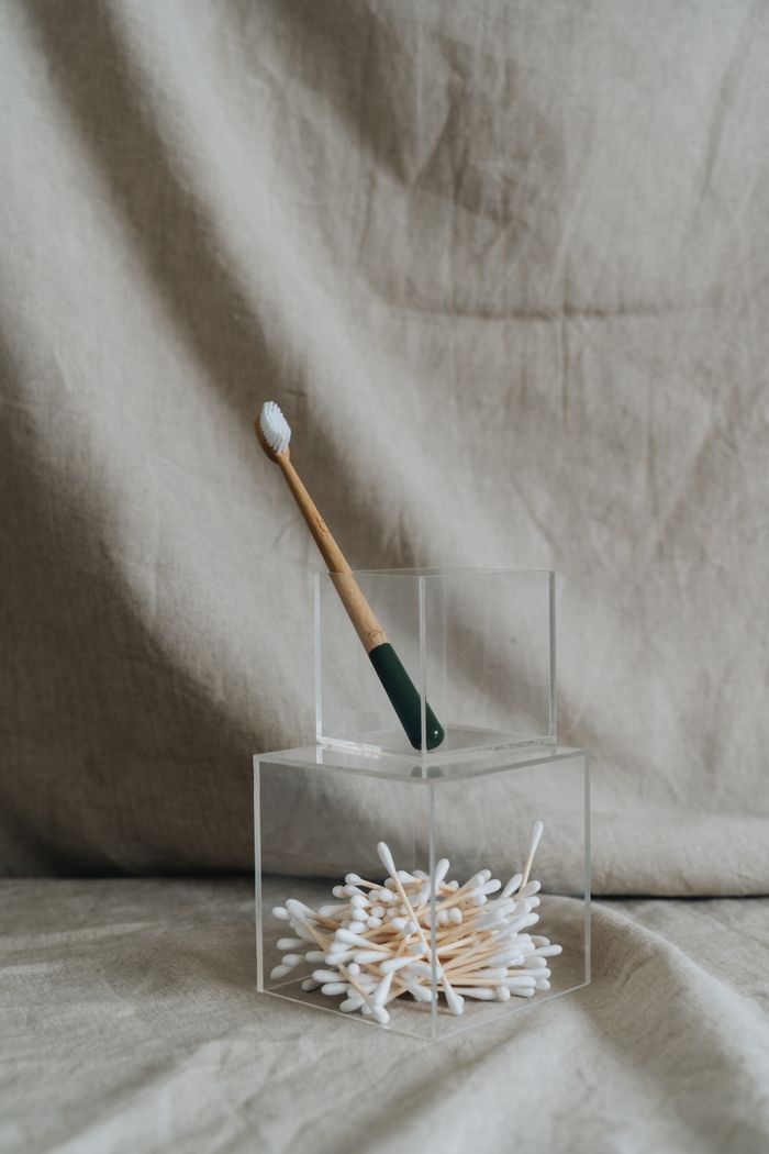 Sustainable bathroom accessories featuring a bamboo toothbrush and cotton swabs in stylish holders.